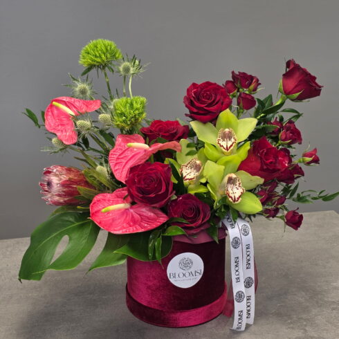 Luxury floral arrangement with red roses, green orchids and anthurium in a velvet BLOOMSI box