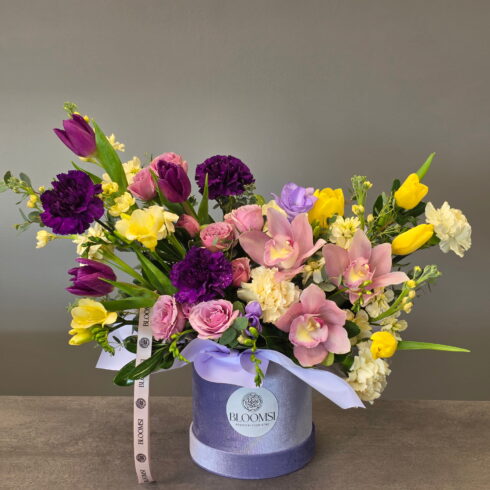 Luxury orchid flower box with pink orchids, purple carnations, yellow tulips and roses in BLOOMSI hat box