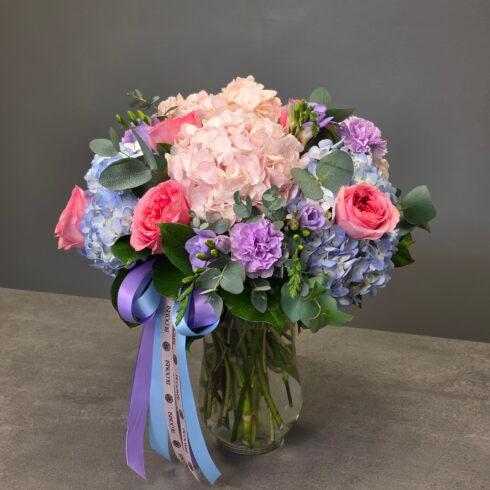 Luxury hydrangea and rose arrangement in glass vase with pastel blue and lavender flowers