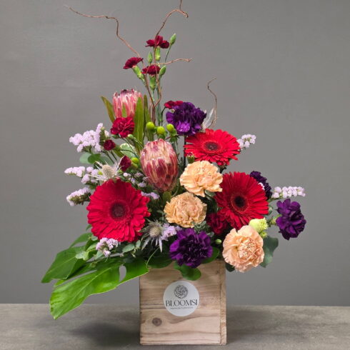 Luxury designer flower arrangement with protea, gerberas, carnations and eucalyptus in wooden box by BLOOMSI Canada