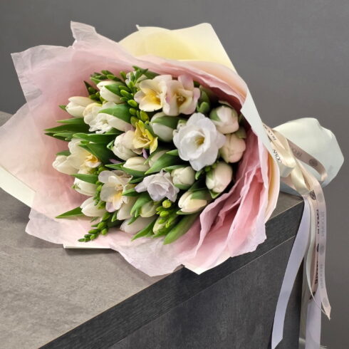 Elegant white tulips and freesia hand-tied bouquet wrapped in blush paper by BLOOMSI Toronto